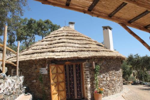 a small stone building with a thatched roof at Alojamiento Los Chozos in Cazalla de la Sierra