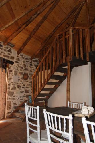 a wooden staircase in a room with white chairs at Alojamiento Los Chozos in Cazalla de la Sierra