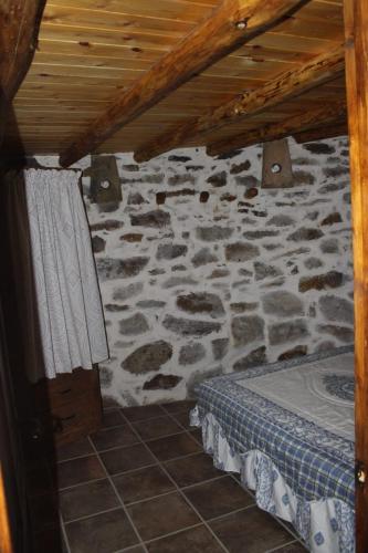 a room with a stone wall with a bed and a door at Alojamiento Los Chozos in Cazalla de la Sierra