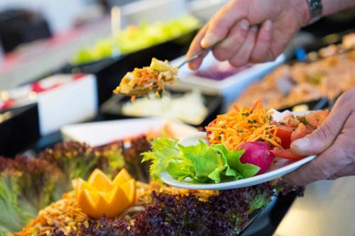 a person is holding a plate of food at Hôtel Club MMV Le Flaine in Flaine