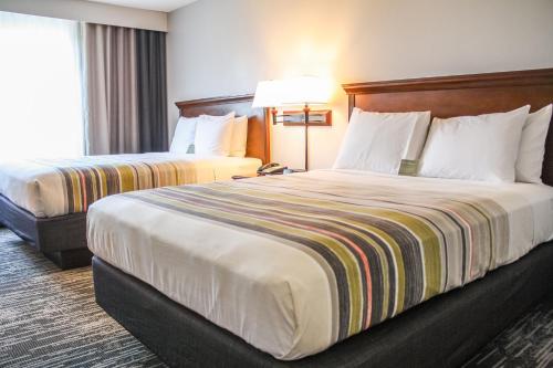 a hotel room with two beds and a lamp at Country Inn & Suites by Radisson, Washington Dulles International Airport, VA in Sterling