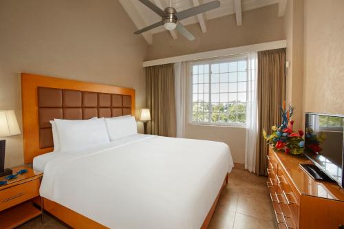 a bedroom with a large white bed and a television at Divi Southwinds Beach Resort in Christ Church