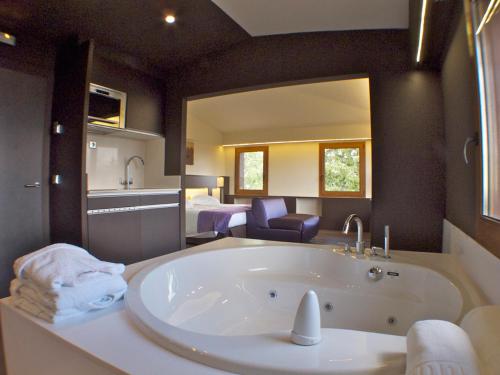 a large bathroom with a tub and a bedroom at Hotel Mirador in Lles