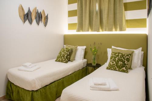 2 Betten in einem Zimmer mit weißen und grünen Kissen in der Unterkunft Casa Ercoli BOITO in Vinci
