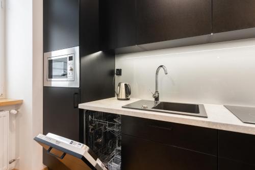 een keuken met een wastafel en een magnetron bij Bridge Apartments 6 in Krakau