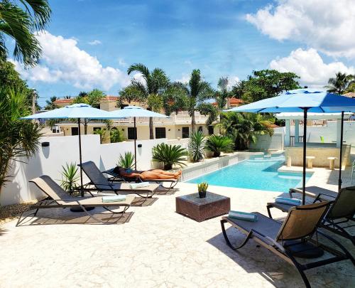 un grupo de sillas y sombrillas junto a una piscina en Casa Verde Hotel, en Rincón