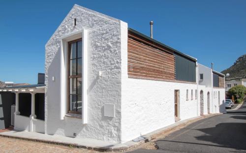 a white building with a wooden roof on a street at Rosmead Apartment in Kalk Bay