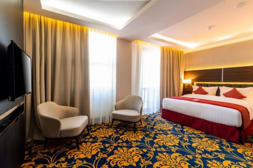a hotel room with a bed and two chairs at Ramada Hotel & Suites by Wyndham Yerevan in Yerevan