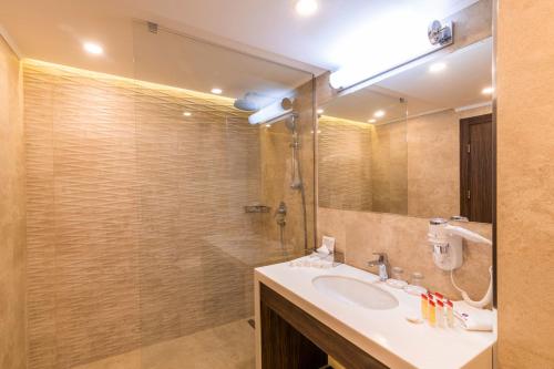 a bathroom with a sink and a shower with a mirror at Ramada Hotel & Suites by Wyndham Yerevan in Yerevan