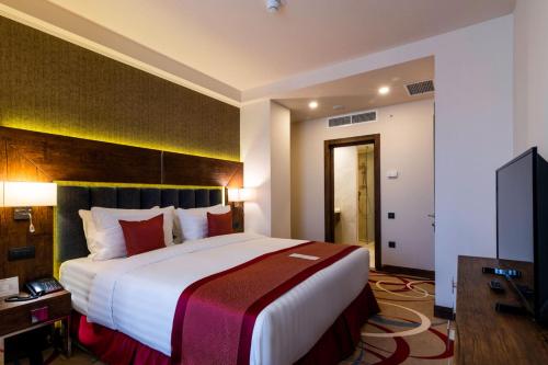 a hotel room with a large bed and a television at Ramada Hotel & Suites by Wyndham Yerevan in Yerevan