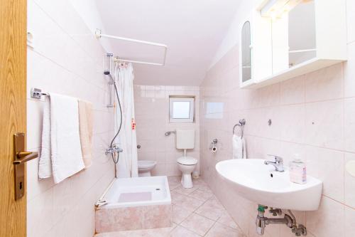 a white bathroom with a sink and a toilet at Apartmani Villa Mimi in Brodarica
