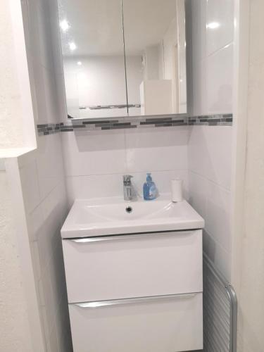 une salle de bain blanche avec un lavabo et un miroir dans l'établissement Le Studio De Deauville Plage, à Deauville