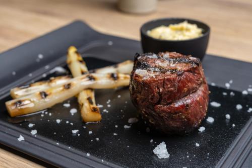 a steak and french fries on a black plate at Eurostars Palacio de Cristal in Oviedo