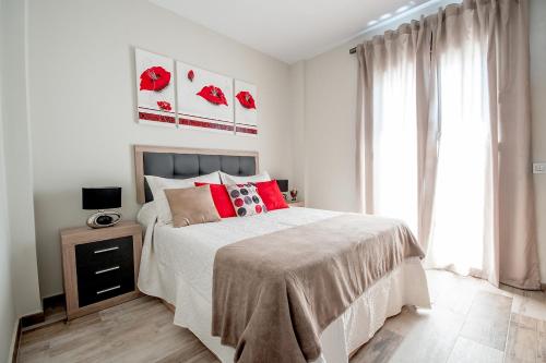Cubo's Urban Suite Town Centre في لاورين إل غراندي: غرفة نوم بسرير كبير ومخدات حمراء