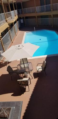 a swimming pool with chairs and an umbrella and a swimming pool at Lotus by Hotel Inn in Ontario