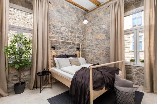 1 dormitorio con pared de piedra, cama y ventanas en Molo Longo - Central Apartments & Rooms, en Rijeka
