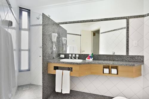 a bathroom with a sink and a mirror at Plaza Inn Flat Araxá in Araxá