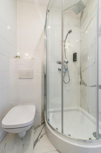 a white bathroom with a shower and a toilet at Panorama Przemyśl in Przemyśl
