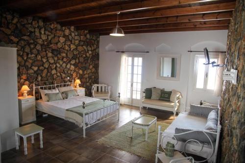 a bedroom with two beds and a stone wall at Vareladiko studios in Alinda