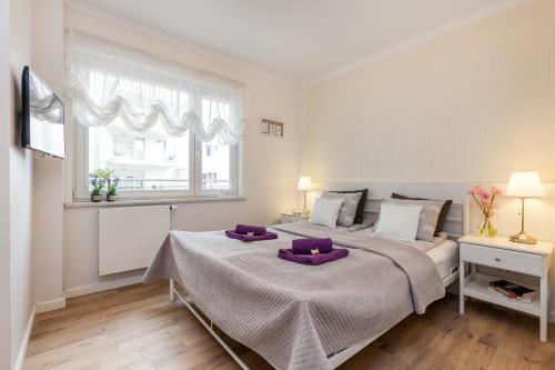 グディニャにあるApartamenty Black&White - Silver Houseのベッドルーム1室(紫色の枕が付いた大型ベッド1台付)