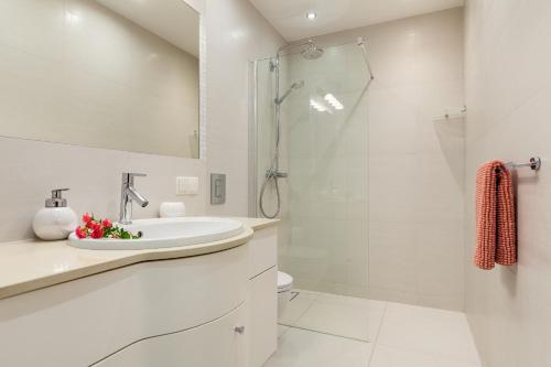 a white bathroom with a sink and a shower at Apartamenty Black&White - Silver House in Gdynia