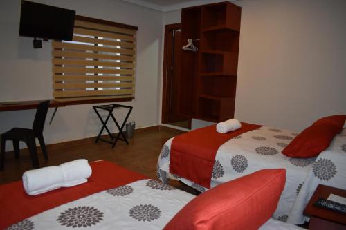 a bedroom with two beds and a desk and a window at Hotel Boutique Vendimia in Tarija