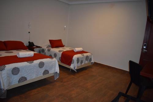 a bedroom with two beds and a chair in it at Hotel Boutique Vendimia in Tarija