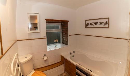 a white bathroom with a tub and a window at Eithin Bach in Caernarfon