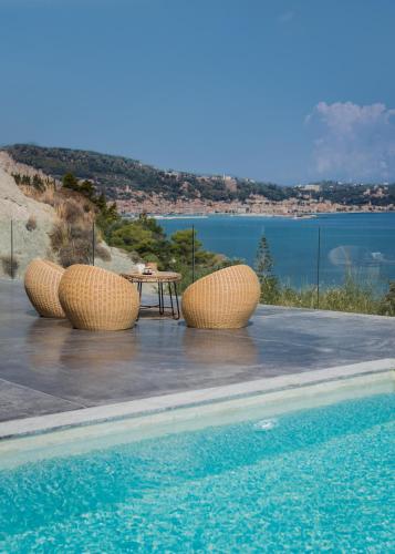 a pool with three straw chairs and a table and water at Sueño LUXURY VILLA, in Argasi 180 Iconic Sea View in Argasi