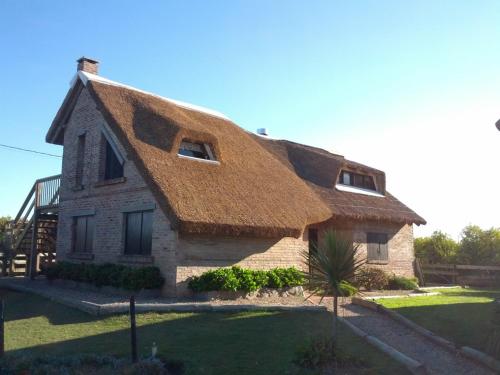 a thatch roofed house with a grass at Cabañas Playa Serena in La Paloma