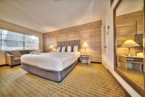 um quarto de hotel com uma cama grande e um sofá em Club Lux Resort By The Beach em Deerfield Beach