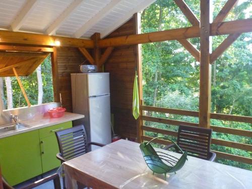 eine Küche mit einem Tisch und Stühlen sowie einem Kühlschrank in der Unterkunft Kaz Luciole in Deshaies
