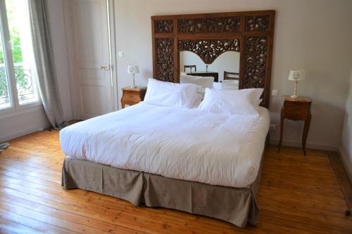 - une chambre avec un grand lit blanc et une tête de lit en bois dans l'établissement La KEFOISE, à Fouquières-lès-Lens