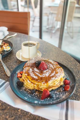 a plate of pancakes with strawberries and a cup of coffee at Warwick Denver in Denver