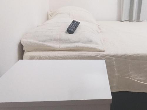 un mando a distancia sentado sobre una cama blanca en Centro, Privado total, Metrô, rodoviária, Copacabana em 10 minutos, SmarTV, en Río de Janeiro