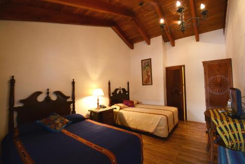 a bedroom with two beds and a table at Hotel Candelaria Antigua in Antigua Guatemala
