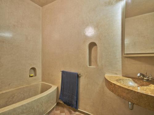 馬拉喀什的住宿－Riad Volubilis，带浴缸、水槽和蓝毛巾的浴室