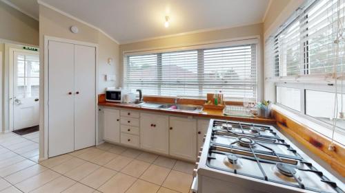 a kitchen with a stove and a sink and windows at Regent Residential Villa in Whangarei