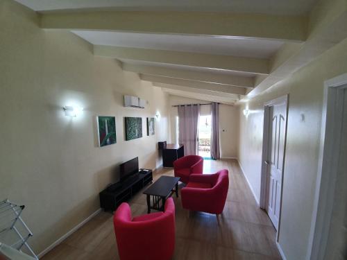 a living room with red chairs and a television at Le Uaina Beach Resort in Falepuna