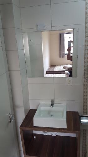 uma casa de banho com um lavatório branco e um espelho. em Novo Lar Meia Praia 1 England em Itapema