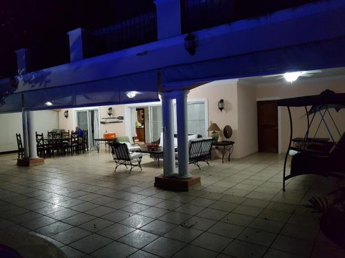 a patio with chairs and tables and a blue umbrella at Villa M-6 Metro Country Club in Juan Dolio