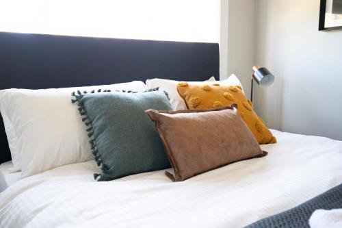 a white bed with many pillows on it at Horse and Jockey Hotel Homebush in Sydney