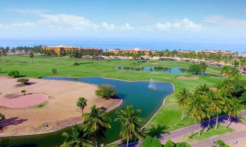 an aerial view of a golf course with palm trees and water at Luxury Suites By Estrella del Mar in Mazatlán