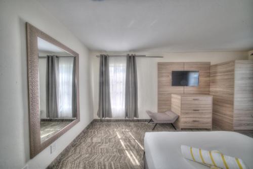 a bedroom with a bed and a mirror and a chair at Riverside by the Beach Apartments in Pompano Beach