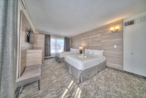 a hotel room with two beds and a television at Riverside by the Beach Apartments in Pompano Beach