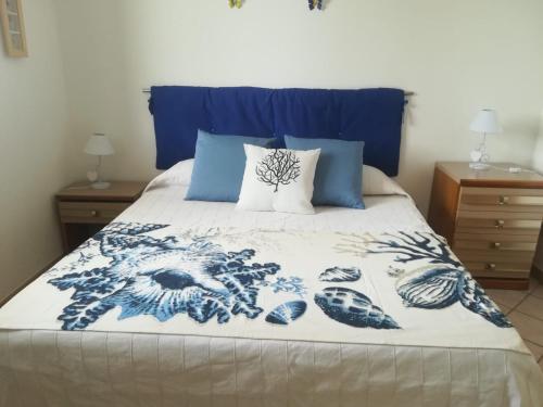 a bed with a blue and white blanket and pillows at APARTMENT IN VILLA (NEAR THE SEA) in Porto Palo