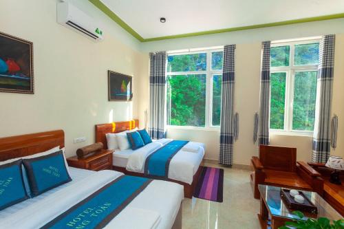 two beds in a room with two windows at Song Toan Hotel in Phong Nha