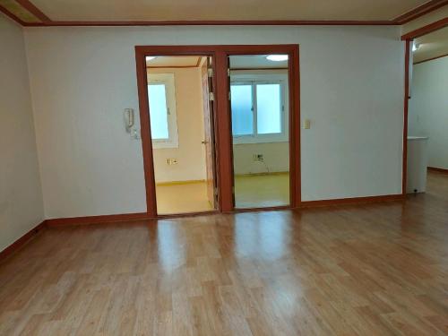 an empty room with wooden floors and sliding doors at Gimhae Guest House in Gimhae