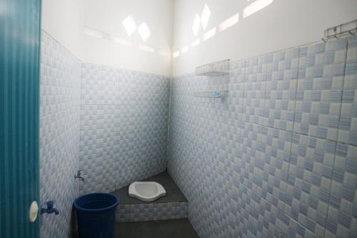 a bathroom with a toilet and a blue tiled wall at West Surabaya Homey in Surabaya