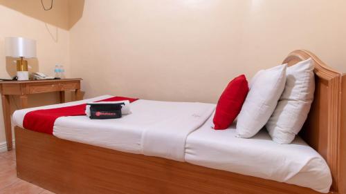 a bedroom with a bed with red and white pillows at RedDoorz @ Downtown Tacloban in Tacloban